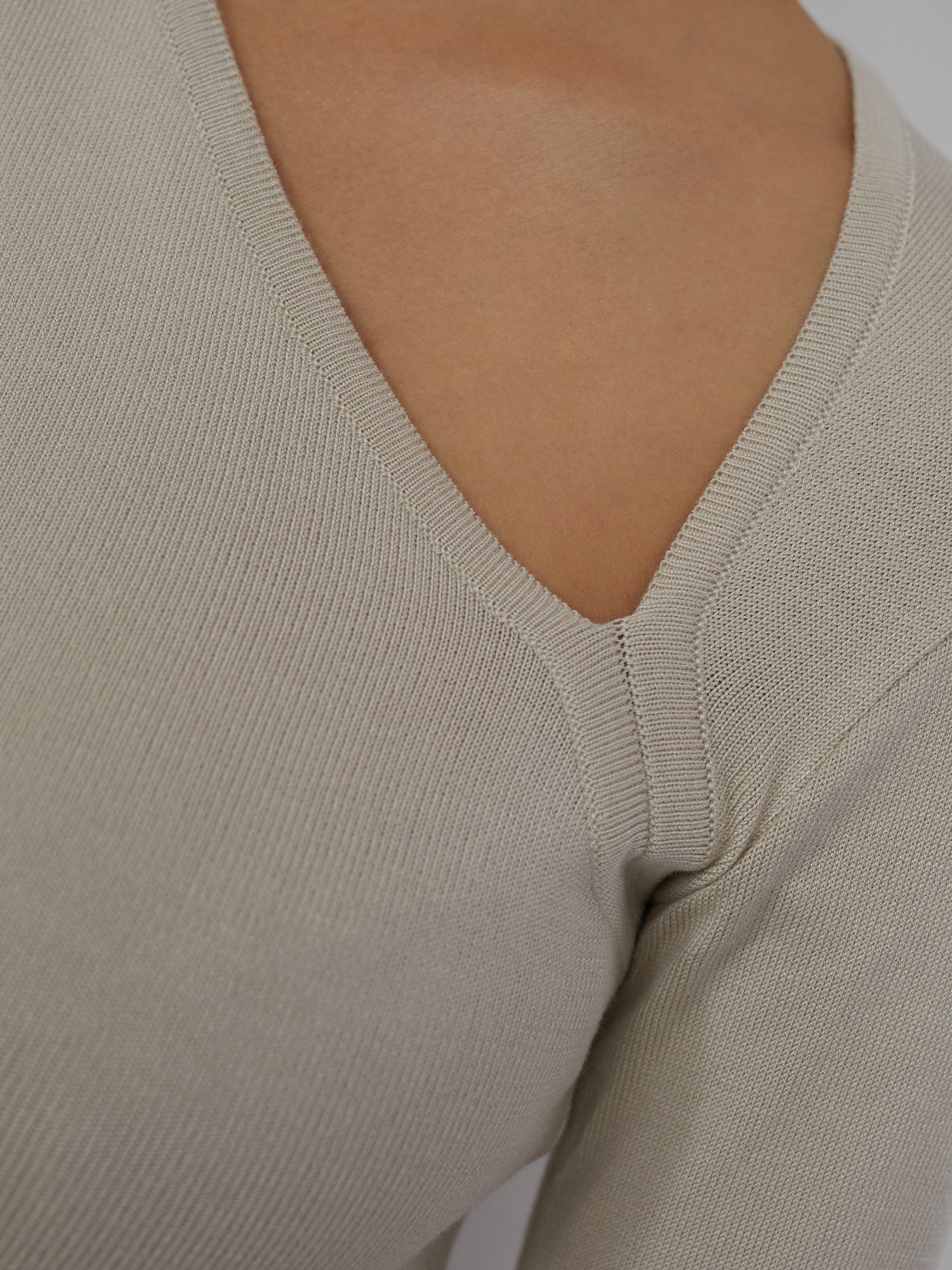 Eine Nahaufnahme zeigt jemanden, der das Helen Top von LeGer by Lena Gercke trägt. Das beige Strickdesign mit ausgeschnittenen Schultern ist ein Blickfang. Der weiche Stoff weist ein sichtbares Webmuster auf und bietet eine schmale Passform und normale Länge mit langen Ärmeln für einen schicken Stil.